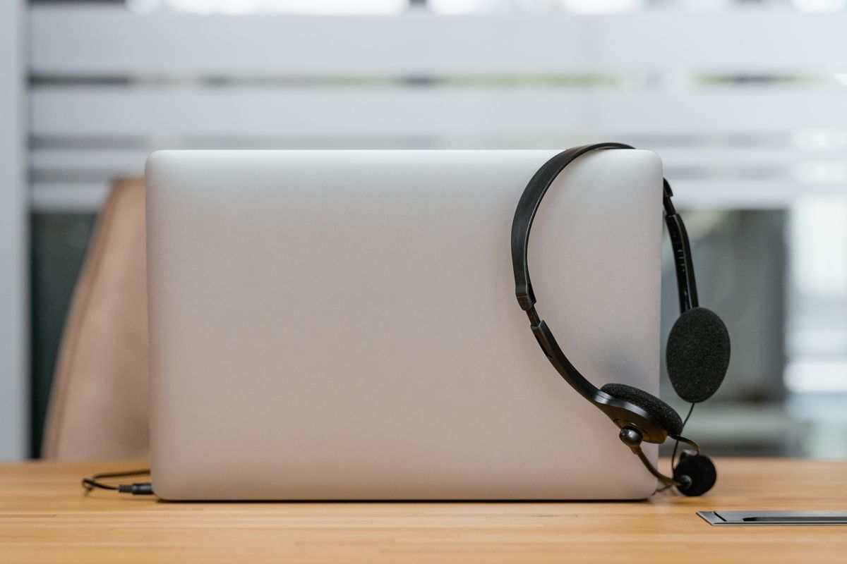 Headset de atendimento apoiado em um notebook sobre a mesa.